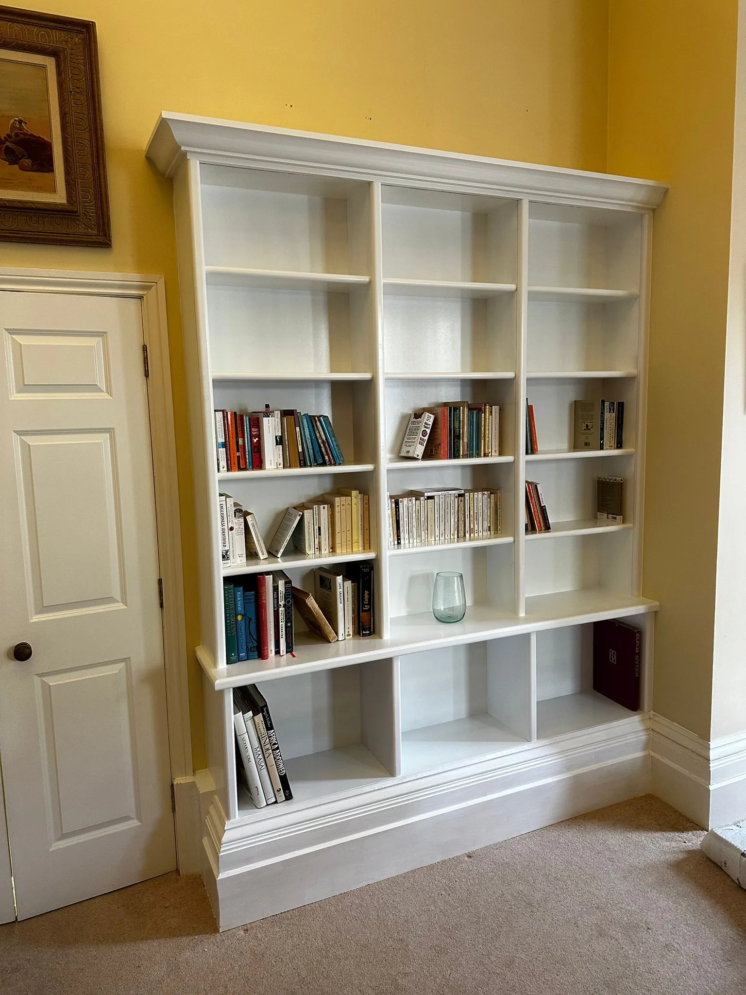 a white book shelf with many books on it