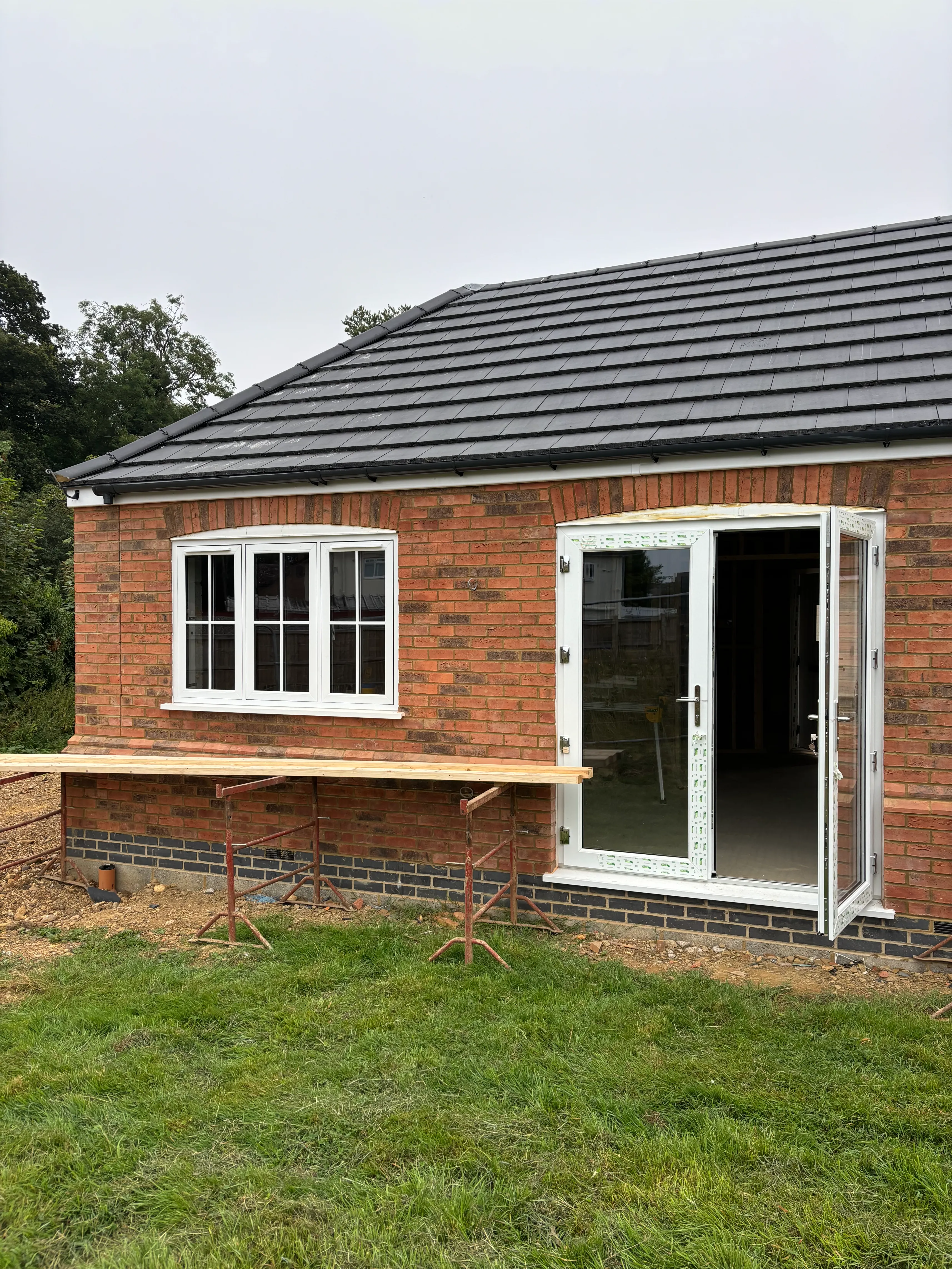 A small brick building with a patio and sliding glass doors.