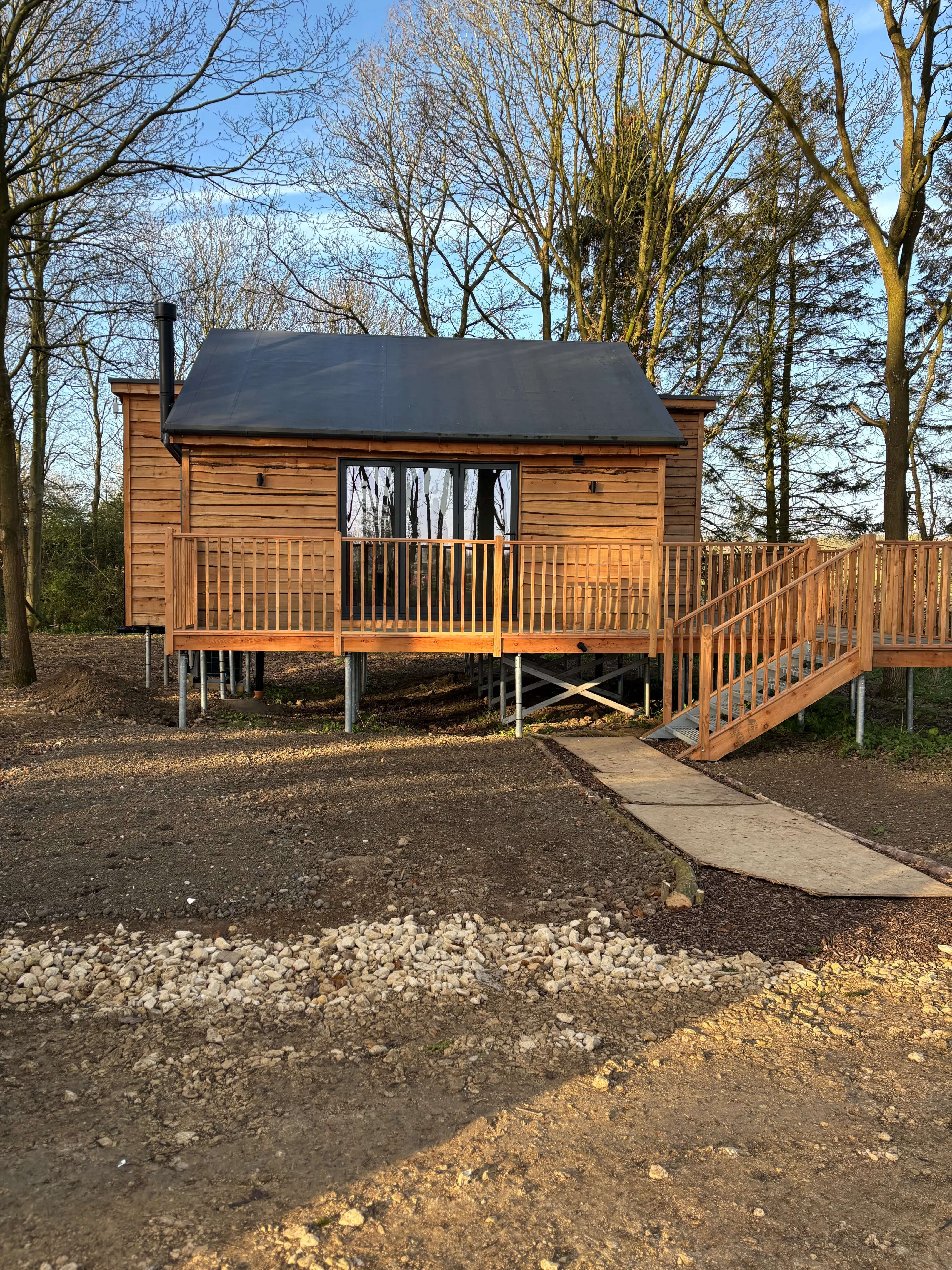 A wooden cabin in the woods with a walkway leading to it.