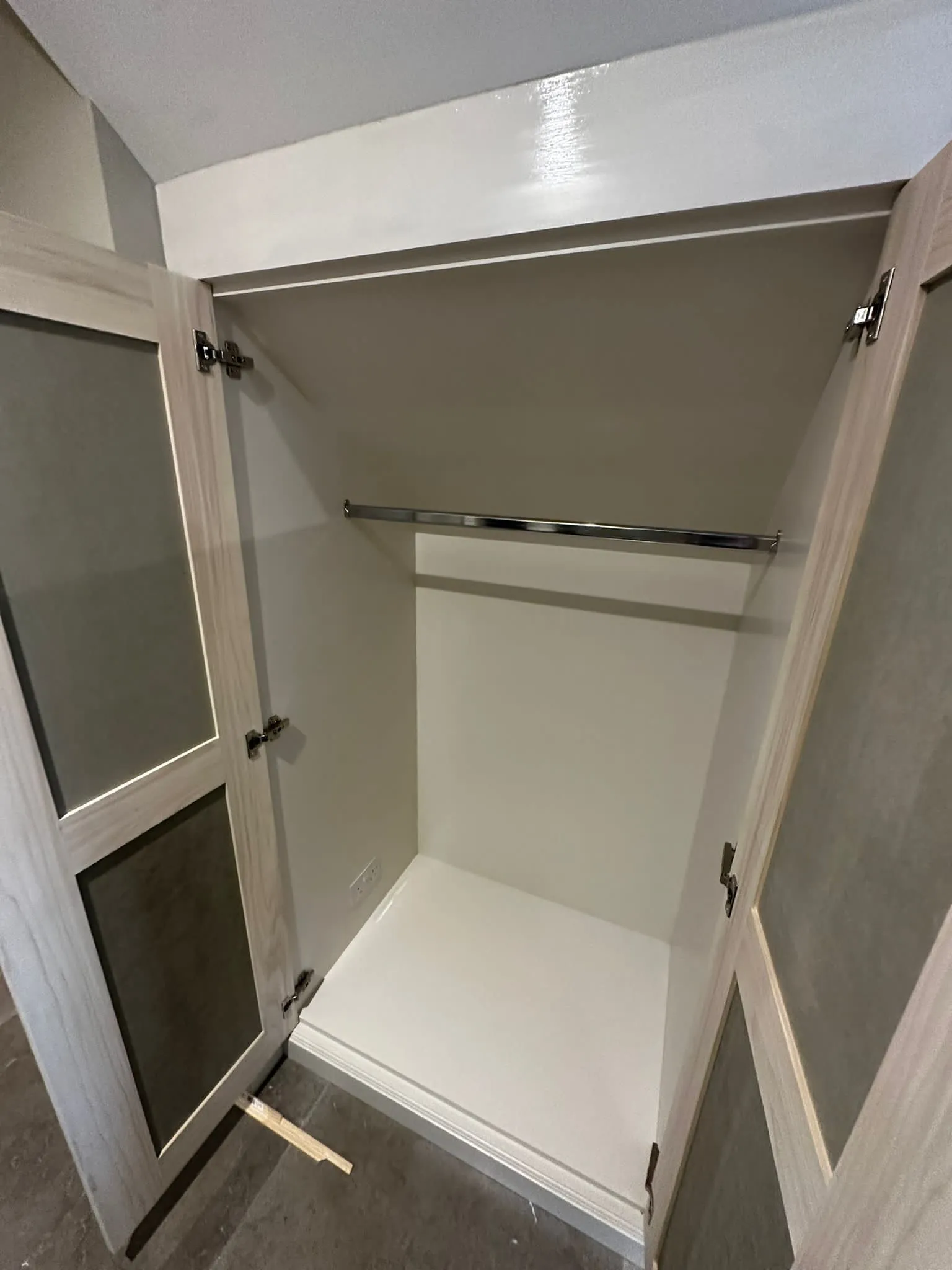 a white closet with two doors and a shelf