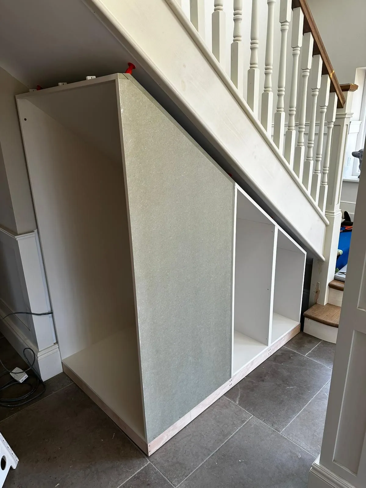 a white cabinet under a stair case in a house